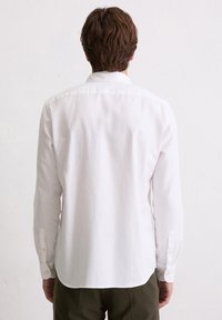 Witte langemouwen overhemd met een button-down kraag, achterplooien en een ronde onderkant. Kenmerkt knoopmanchetten en een lichtgewicht katoenen textuur.