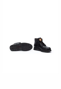 Bottines en cuir noir avec une surface texturée, un design à lacets et une semelle en caoutchouc robuste. La fermeture éclair sur le côté et le col rembourré ajoutent des détails.