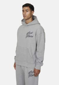 Szara bluza z kapturem wykonana z miksu bawełny, z przednią kieszenią i nadrukowanym logo "Good for Nothing" na klatce piersiowej.