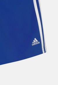 Šortky Adidas v �živé modré barvě, s bílými pruhy po stranách a bílým logem Adidas na dolní části.