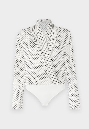 Blusa bianca con pois neri, maniche lunghe e design drappeggiato. Presenta un fondo a body bianco. Tessuto dalla consistenza liscia.