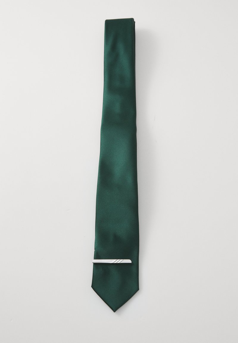 Cravate en soie verte avec une texture lisse, dotée d'une pince à cravate en argent avec un motif diagonal. L'extrémité est pointue.