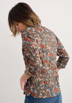 Brown floral blouse with a gathered back, featuring blue, red, and green patterns. Long sleeves with rolled cuffs, made from lightweight fabric.
