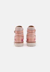 Botas de tobillo de cuero rosa con tela acolchada en la parte trasera, correas laterales y una suela de goma blanca. Presentan un acabado ligeramente desgastado.