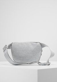 Grå tyg slingväska med rektangulär form, justerbar rem, slät textur och dragkedjestängning. Diskret melerat detaljer genom hela väskan.
