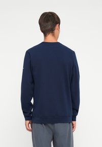 Felpa a maniche lunghe blu navy con scollatura a girocollo e polsini elastici. Realizzata in morbido misto cotone, design semplice senza motivi prominenti.