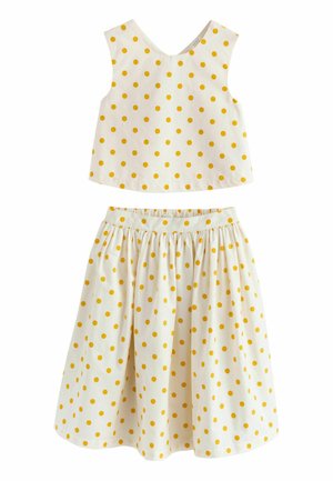 Biały bezrękawnik krótki top i marszczona spódnica w żółte groszki, zaprojektowane dla dziewczynek.