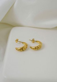 Boucles d'oreilles en or avec une texture torsadée. Petite tige à l'arrière, présentant une finition brillante et un design incurvé en forme de coquillage.
