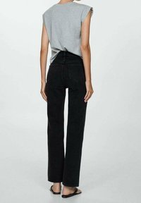 Top gris sin mangas con escote redondeado, combinado con jeans negros de tiro alto y pierna recta, que cuentan con bolsillos traseros y un diseño limpio.