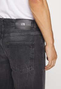 Jeans in denim neri con una trama liscia, dotati di tasche posteriori e di un'etichetta nera rettangolare impressa con la scritta "LTB" sulla vita.