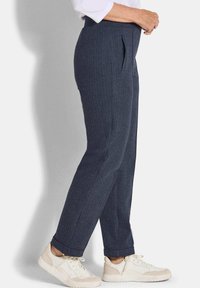 Marineblauwe houndstooth broek met zijzakken, voorzien van een taps toelopende pijp en omgeslagen boorden, gecombineerd met witte sneakers.
