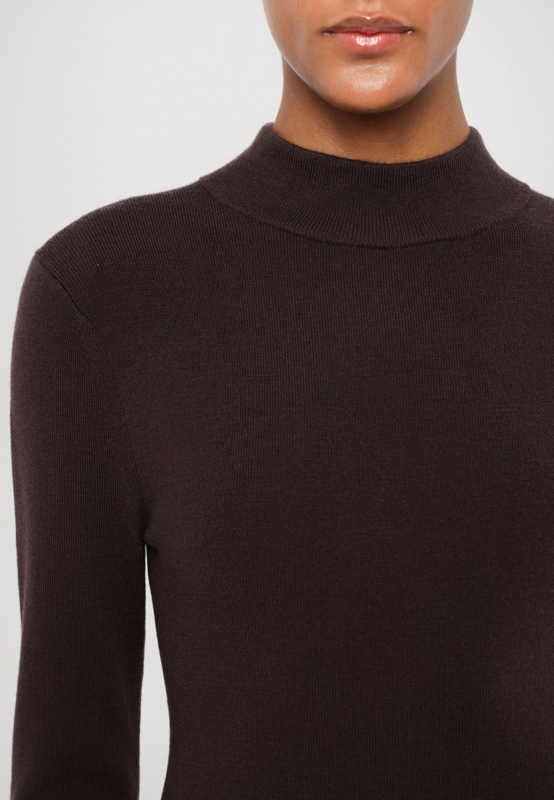 Maglione a coste marrone con colletto alto e maniche lunghe, caratterizzato da una superficie liscia e una silhouette aderente.