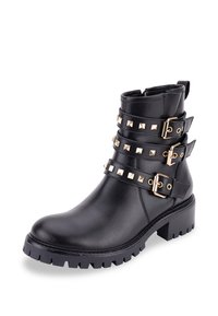 Bota de tobillo de cuero negro con tachuelas y hebillas en tono dorado, con una suela texturizada y un tacón grueso para mayor soporte.