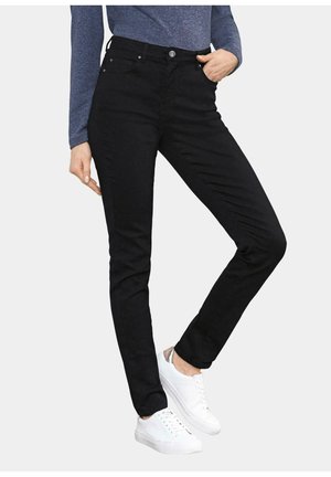 Zwarte slim-fit jeans met een gladde textuur, hoge taille, vijf zakken en zilveren hardware. Gecombineerd met witte sneakers.