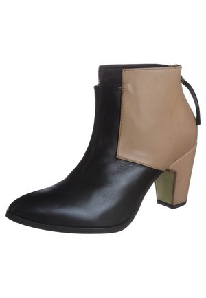 Bottine à bout pointu, devant noir et arrière beige, talon bloc avec détail métallique et fermeture éclair au dos.