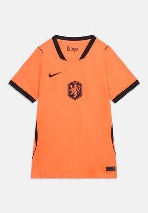 Narancssárga rövid ujjú futballmez fekete gallérral és mandzsettával, oroszlán emblémával és Nike logóval a mellkason.