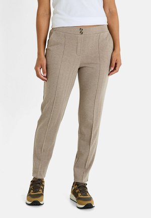 Pantalones de espiga de color marrón claro con un corte ajustado, que presentan dos botones en la cintura y costuras frontales sutiles. Combinados con zapatillas marrones.