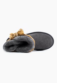 Pantofole in suede grigio con un interno testurizzato, caratterizzate da un'accenno in bandana gialla a fantasia alla caviglia e morbido rivestimento in pelliccia.