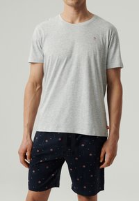 Szara bawełniana koszulka z okrągłym dekoltem. Połączona z granatowymi szortami z drobnym czerwonym kwiatowym wzorem i regulowanym w pasie sznurkiem.