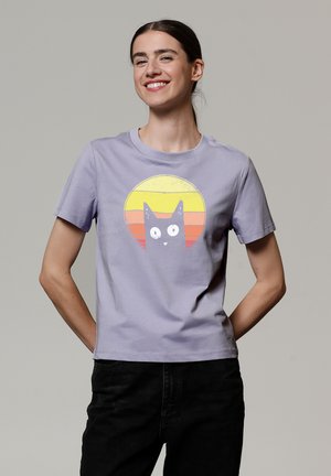 Lila katoen T-shirt met een bedrukte afbeelding van een kat tegen een retro zonontwerp in gele en oranje tinten. Korte mouwen en ronde hals.