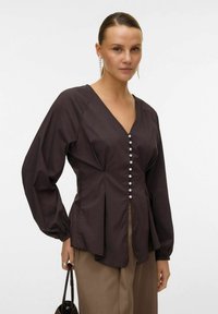 Braunes, Baumwollmischung-Oberteil mit V-Ausschnitt, langen Ärmeln und Perlenknöpfen auf der Vorderseite. Der gefältelte Schnitt sorgt für Struktur und Textur.