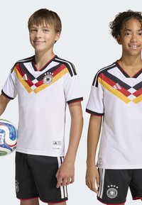 White soccer jerseys with black, red, and yellow chevron patterns and accents. Black shorts with three white stripes and German team logo.