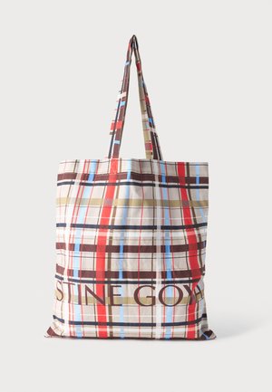 Tote bag with long handles in beige fabric featuring red, blue, brown, and olive plaid pattern and partial dark text on the front.