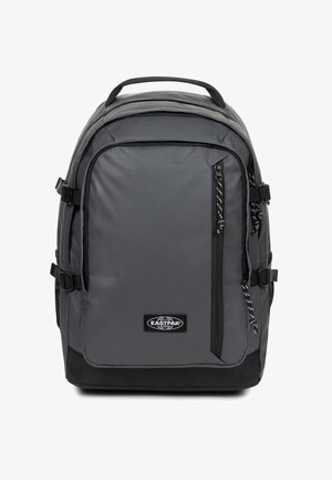 Zaino grigio con finitura testurizzata, multiple cerniere, spallacci regolabili e patch con logo. Caratterizzato da un design strutturato e base rinforzata.