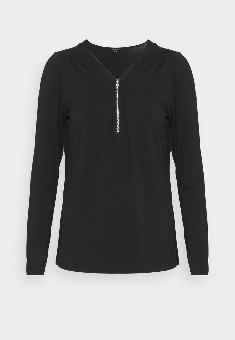 Sort langærmet damebluse med sølvfarvet lynlås foran og let rynkede detaljer ved halsudskæringen, vist på en ensfarvet baggrund.