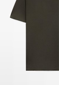 Dunkelolivgrünes T-Shirt mit kurzen Ärmeln flachliegend, Fokus auf rechte Seite und Ärmelsaum vor weißem Hintergrund.