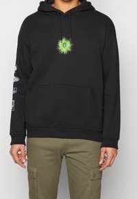 Sudadera negra con bolsillo canguro y capucha con cordón. Presenta un gráfico verde brillante en el centro y gráficos blancos en la manga izquierda.