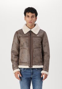 Rudas dirbtinio odos striukė su minkštu baltu avikailio apykakle ir rankogaliais. Turinti užtrauktuką ir dvi priekinės kišenes.