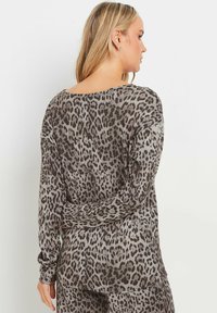Maglia a maniche lunghe in materiale morbido e leggero con una fantasia a stampa leopardata grigia e nera, caratterizzata da un collo rotondo e una vestibilità rilassata.
