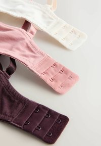 Trois bretelles de soutien-gorge en blanc, rose et violet foncé, dotées de fermetures à crochets et œillets et d'une texture de tissu douce. Chaque bretelle a des éléments ajustables.