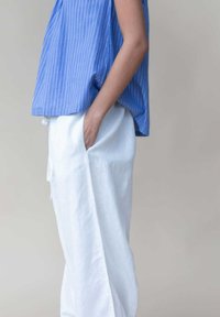 Blauw gestreepte mouwloze top met een relaxte pasvorm, gecombineerd met witte linnen broek met brede pijpen en zijzakken. Glad textuur en licht materiaal.