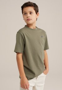 Olivgrön kortärmad t-shirt i mjuk bomull. Har rund halsringning och en liten broderad logotyp på vänster bröst.