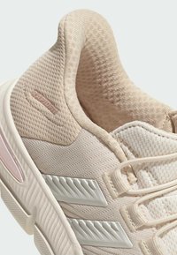 Zapatilla deportiva beige claro con parte superior texturizada, detalles de malla y suela de goma blanca. Presenta la marca "RAPIDEN" y un diseño de rayas diagonales.