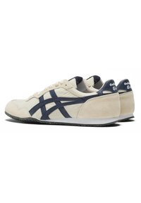 Sneaker beige con accenti blu navy, materiali in suede e tessuto, punta arrotondata, suola in gomma piatta e sistema di lacci. Logo del marchio sul tallone.