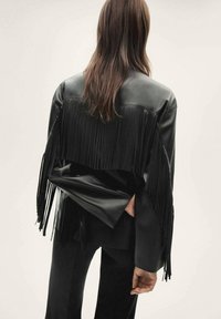 Czarna skórzana kurtka z frędzlami na rękawach i plecach, o gładkiej teksturze i dopasowanym kroju.
