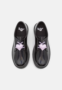 Scarpe in pelle verniciata nera con punta arrotondata, caratterizzate da dettagli a cuore color lavanda sui lacci e suola spessa in gomma.