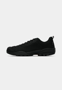 Black athletic shoes made of suede and rubber, featuring a low silhouette, round toe, lace-up design, and textured outsole for grip.