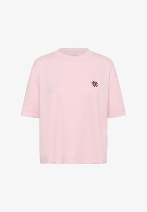 T-shirt rose clair à manches courtes avec encolure ronde, ornée d'une petite broderie de fleur marron sur le côté gauche de la poitrine.
