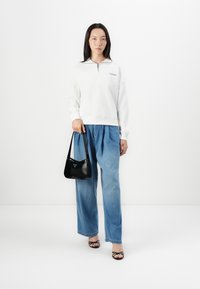 Felpa bianca con zip, jeans a gamba larga azzurri, borsa a tracolla nera. Texture liscia. Tacchi neri con cinturino. Design semplice e moderno.