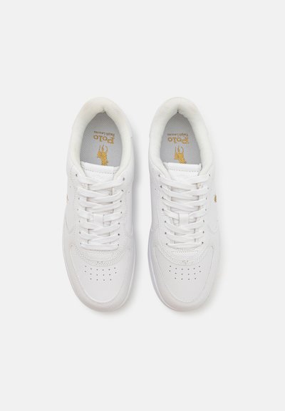 Zapatillas deportivas blancas con parte superior de cuero suave, puntera redonda, detalles perforados y cordones blancos. Logo dorado en la lengüeta.