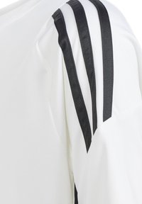 Hvid atletisk skjorte med sort satin tre-stribe design på skulderen. Stoffet virker let; minimalistisk og moderne snit.