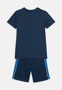 Marinblå bomullströja med rund halsringning ihop med matchande shorts med blå sidostreck och vita detaljer.