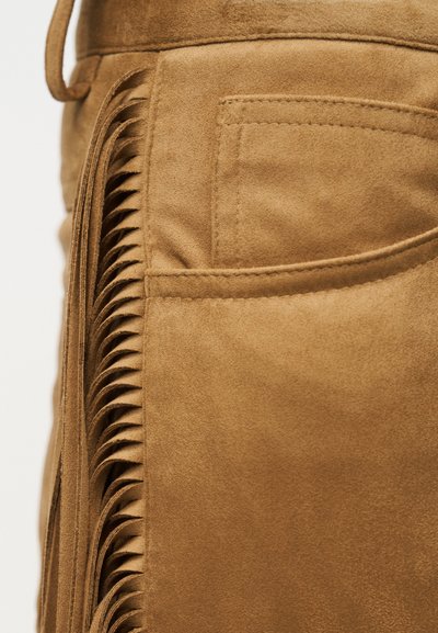 Υλικό σουέτ σε καφέ χρώμα με λεπτομέρειες φουντών κατά μήκος της πλευράς. Διαθέτει τσέπη με ραφές διακριτικές. Απαλή υφή και σύγχρονος σχεδιασμός.