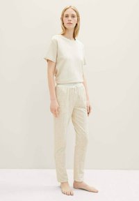 T-shirt en coton beige clair à manches courtes, associé à un pantalon crème à motifs comportant des designs géométriques et une taille élastique.