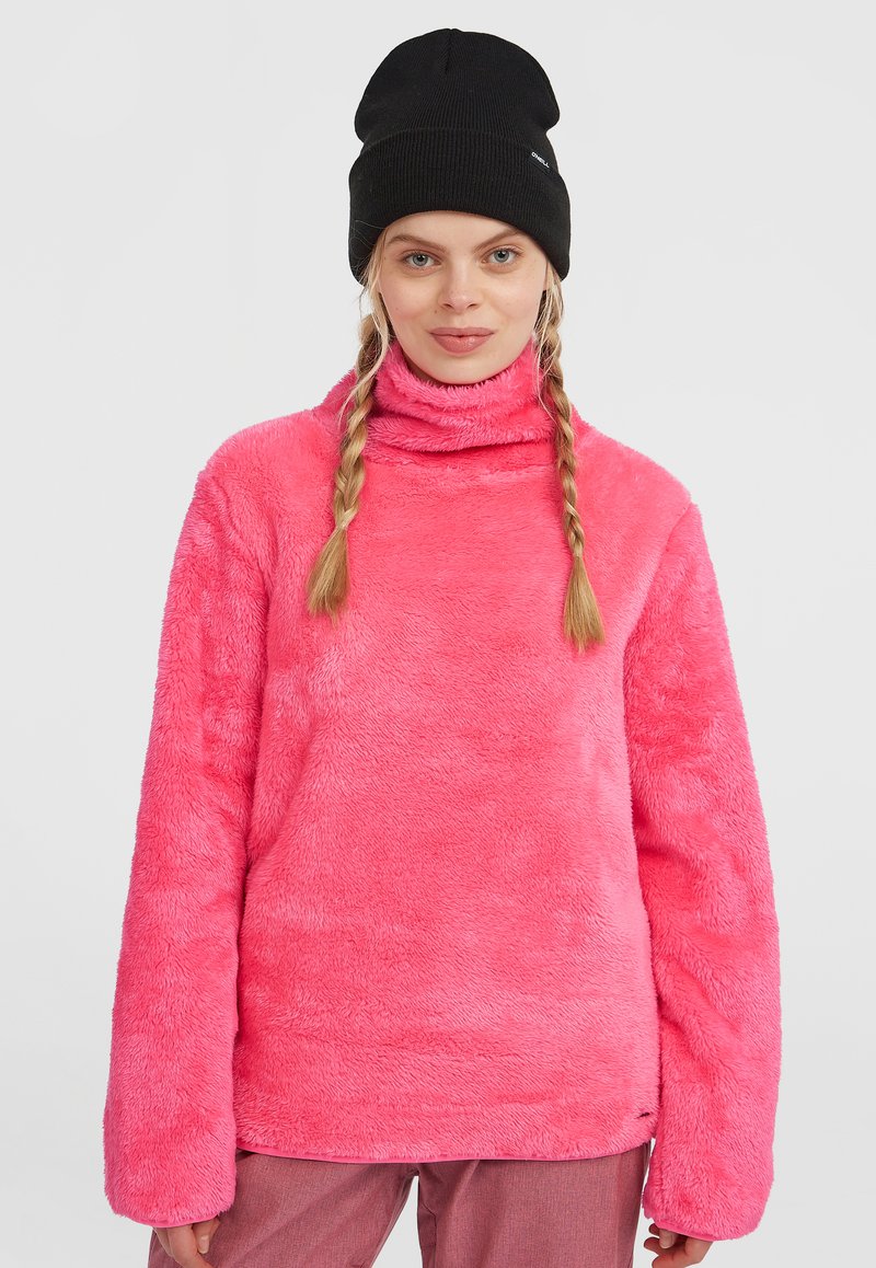 Roze nepbont pullover met een hoge kraag, lange mouwen en een zachte textuur. Het ontwerp heeft een losse pasvorm en wordt gecombineerd met een zwarte beanie.