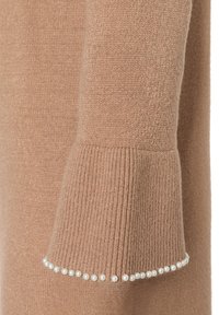 Brauner Strickpullover mit gerippten Bündchen. Bündchen geschmückt mit einer Reihe kleiner weißer Perlen. Sanfte Textur mit einem warmen Aussehen.
